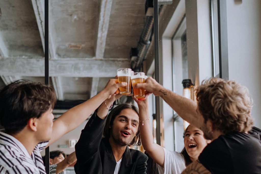 story university north apartments charlotte nc lifestyle photo of a group of four toasting cheers with pint glasses - photodisco 11